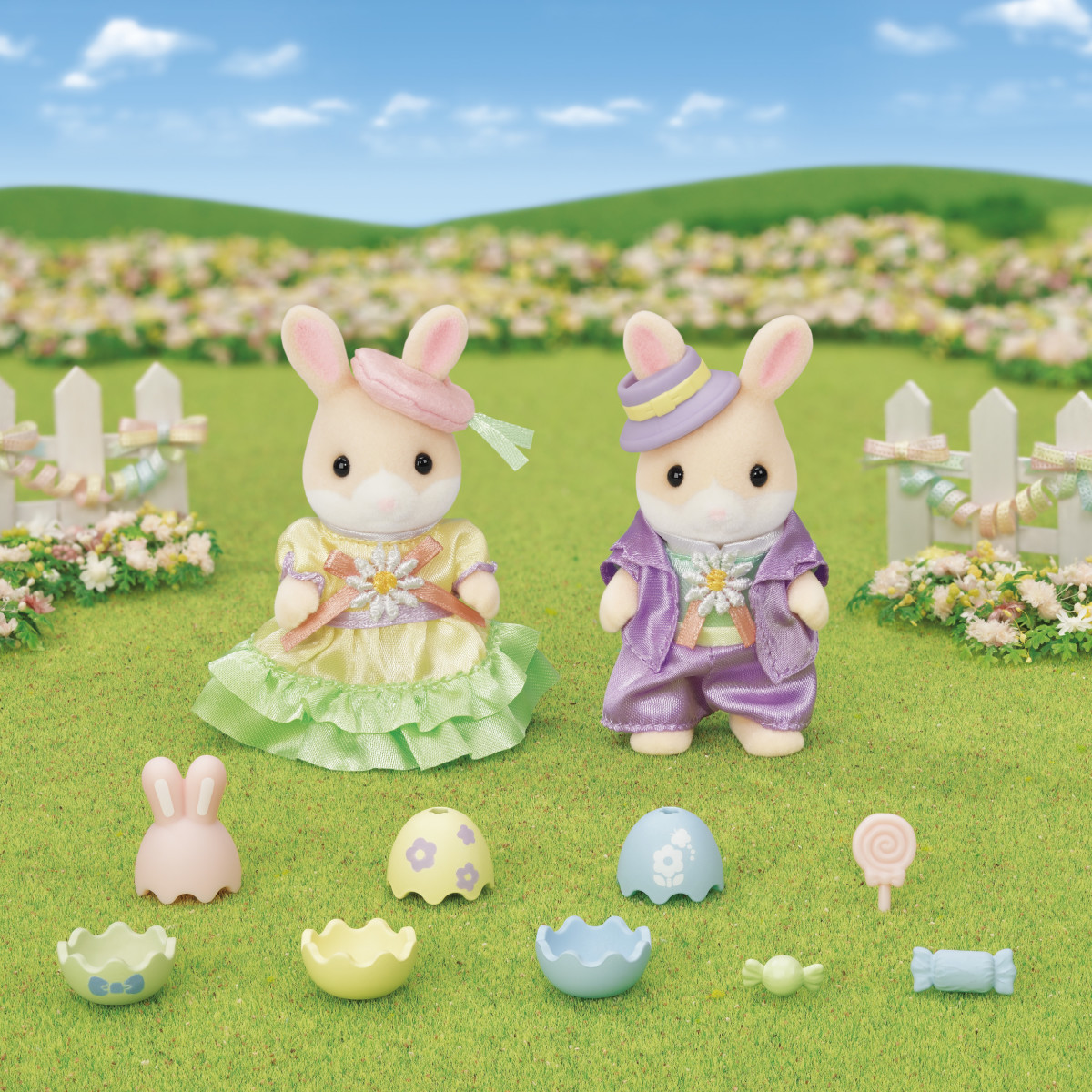 two calico critter bunnies dressed in fancy Easter cloths standing in an idyllic pasture