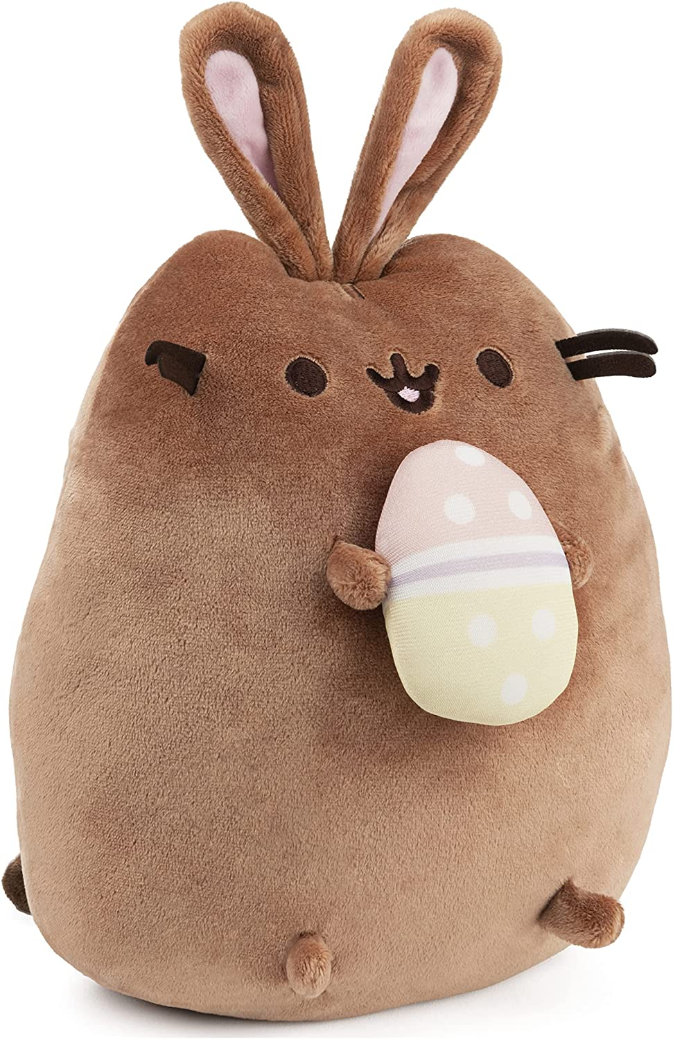 brown cuddly stuffed animal cat name Pusheen with bunny ears and holding an easter egg