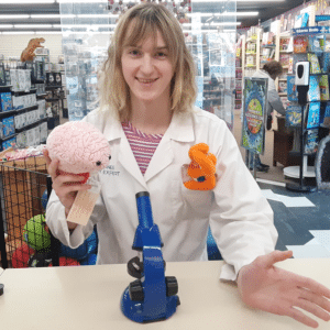 A2Z employ wearing a lab coat posing with microscope and plush brain